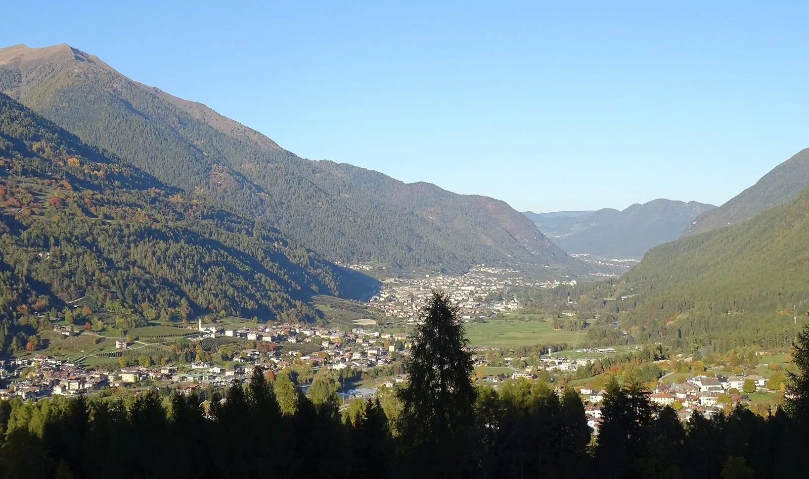 La Val di Sole in autunno vista dall'alto, con i paesi del fondovalle e i boschi che iniziano a cambiare colore