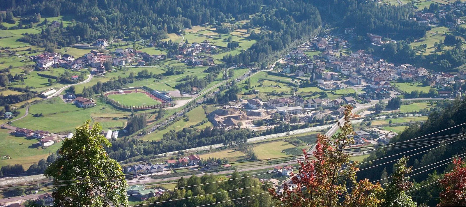 Veduta dall'alto di Dimaro e Carciato nel fondovalle della Val di Sole, con il fiume Noce e i prati