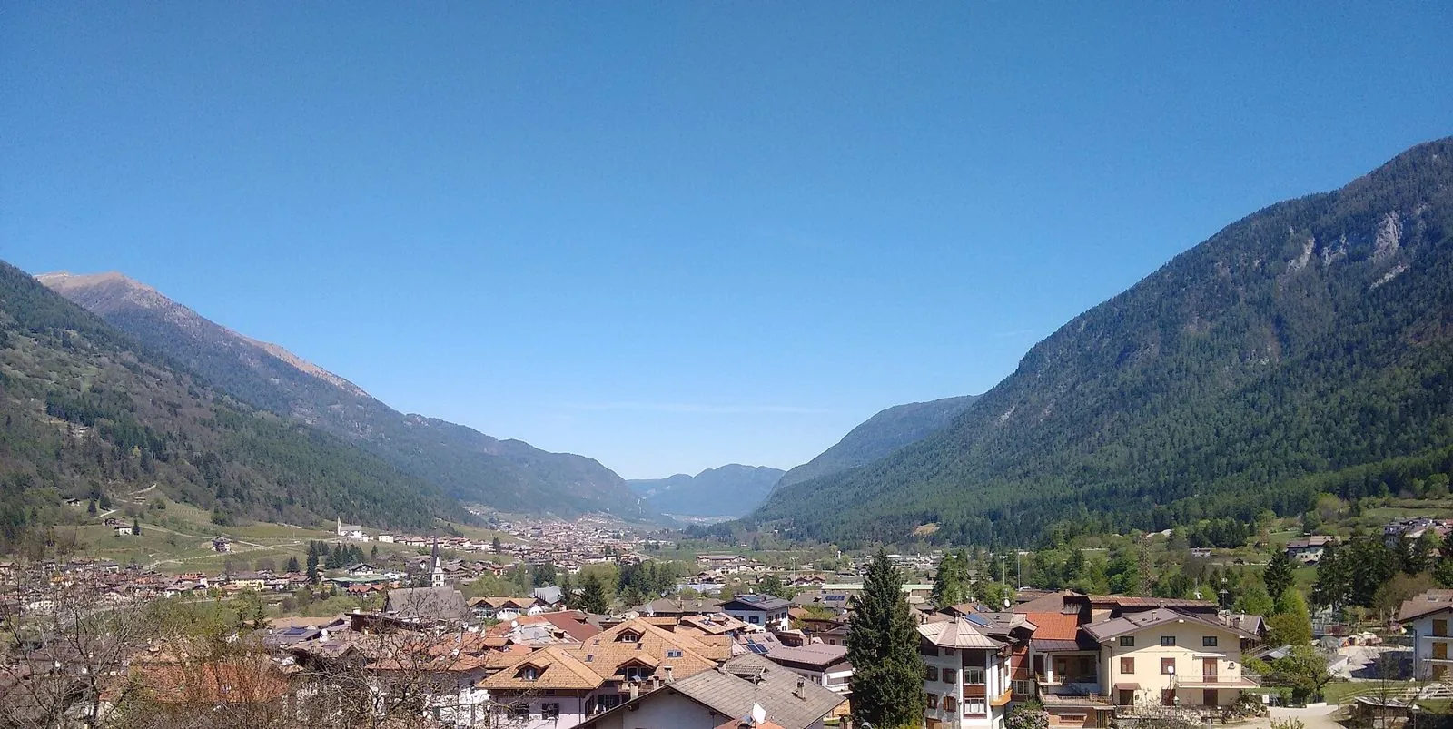 Panorama di Dimaro e della Val di Sole in primavera, con i tetti del paese, i boschi e il cielo limpido